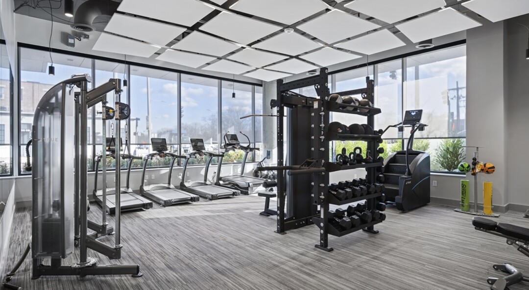 Fitness center with treadmills, strength equipment, and large windows.