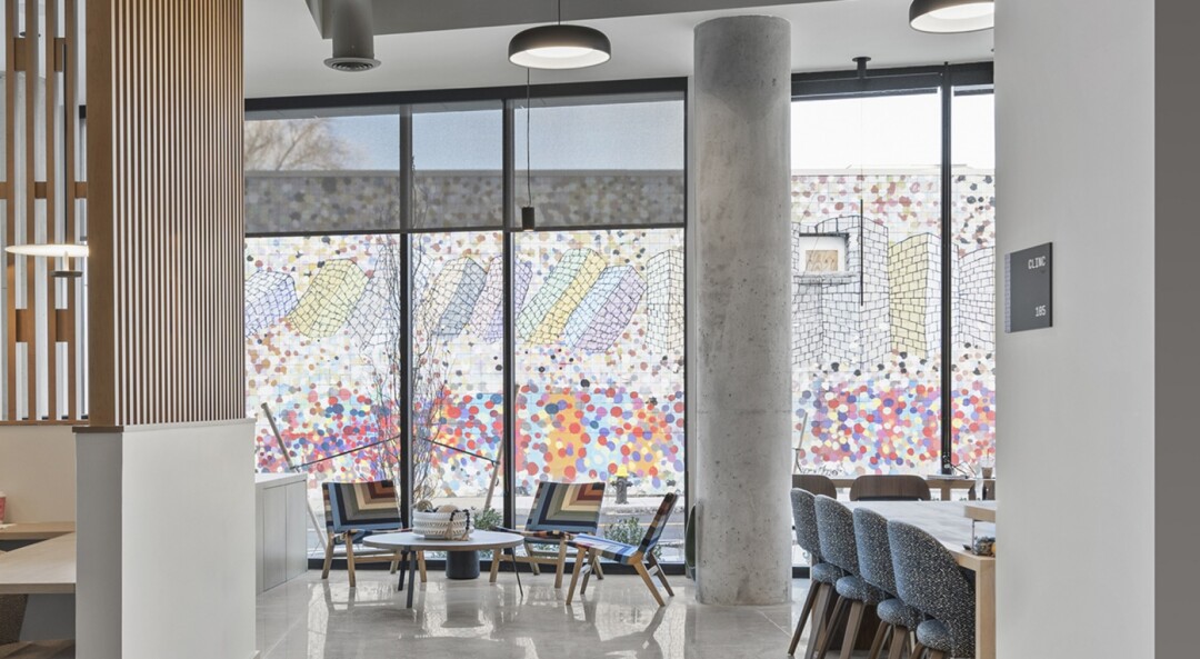 Community room with seating, tables, large windows, and a colorful mural view.