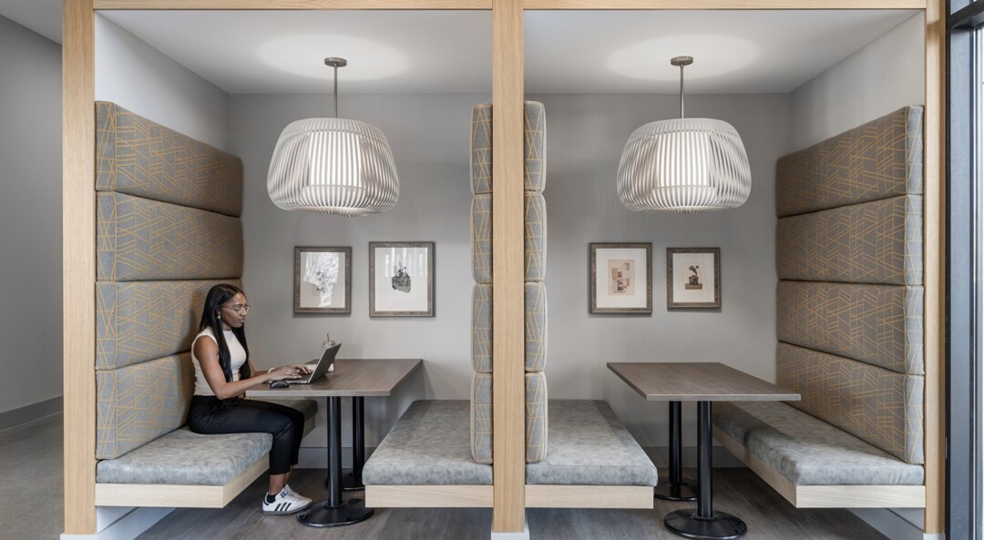 Workstation booths with cushioned seating, tables, and overhead lighting.