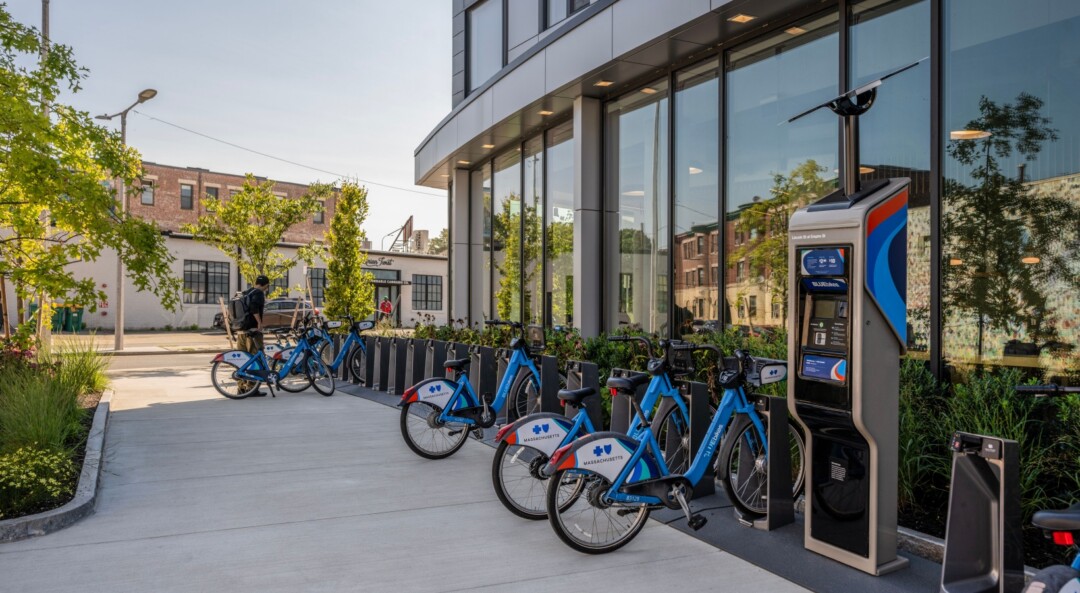 Outdoor bike share station with a paved, landscaped walkway.