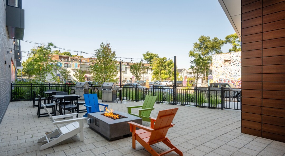 Community patio with tile paver flooring, outdoor seating, fire pit, and grilling area.