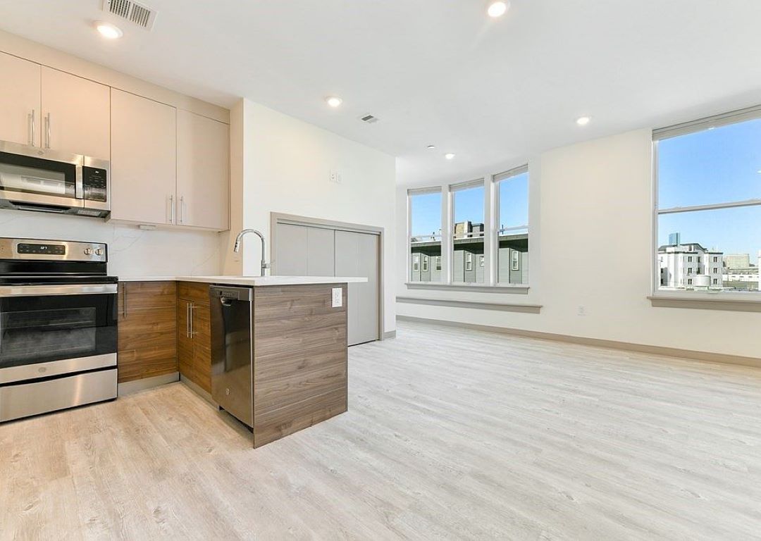 modern kitchen open to living area with stainless steel appliances and wood floors