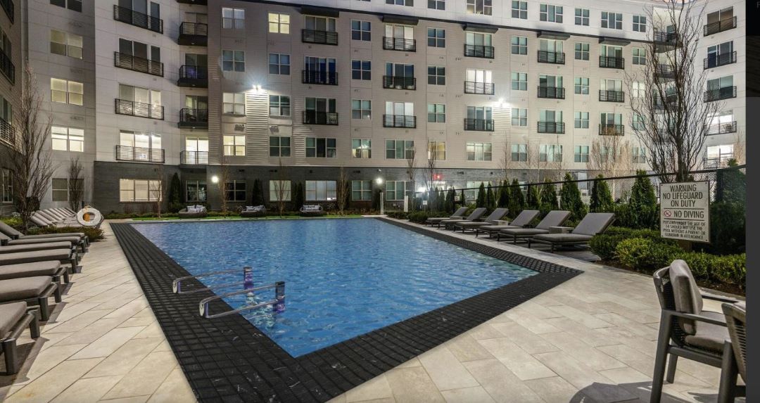 Pool area with lounge chairs and tables at The Nines