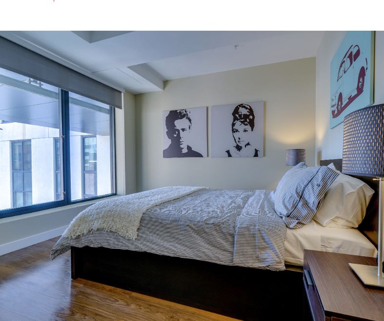 small beige bedroom with picture window and wood floors