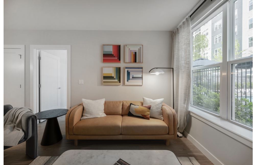 open concept living room off the kitchen with natural light, white walls, and wood floors