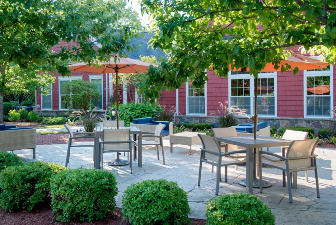 Outdoor dining area with tables, chairs, umbrellas, and surrounding greenery.