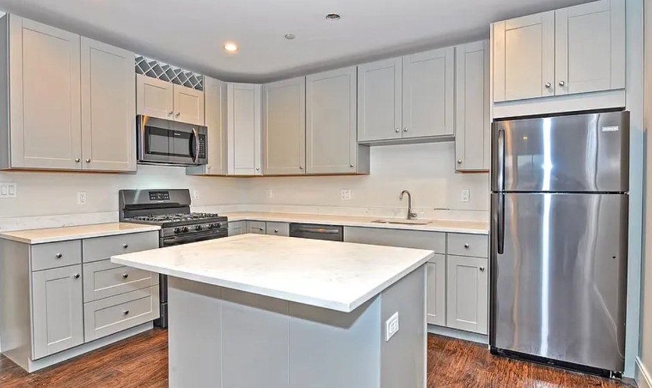 modern kitchen with center island, white cabinets and wood floors