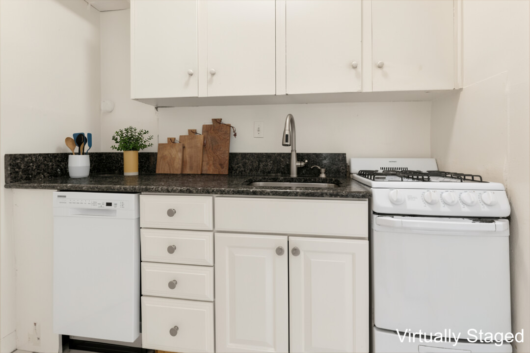 Kitchen with white cabinets, black countertops, white walls, a gas stove, dishwasher, and sink.
