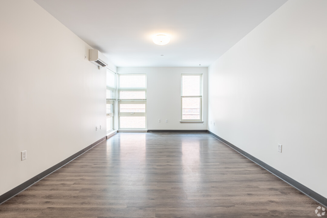 Spacious living room with wood-style flooring, white walls, large windows, and a white ceiling.