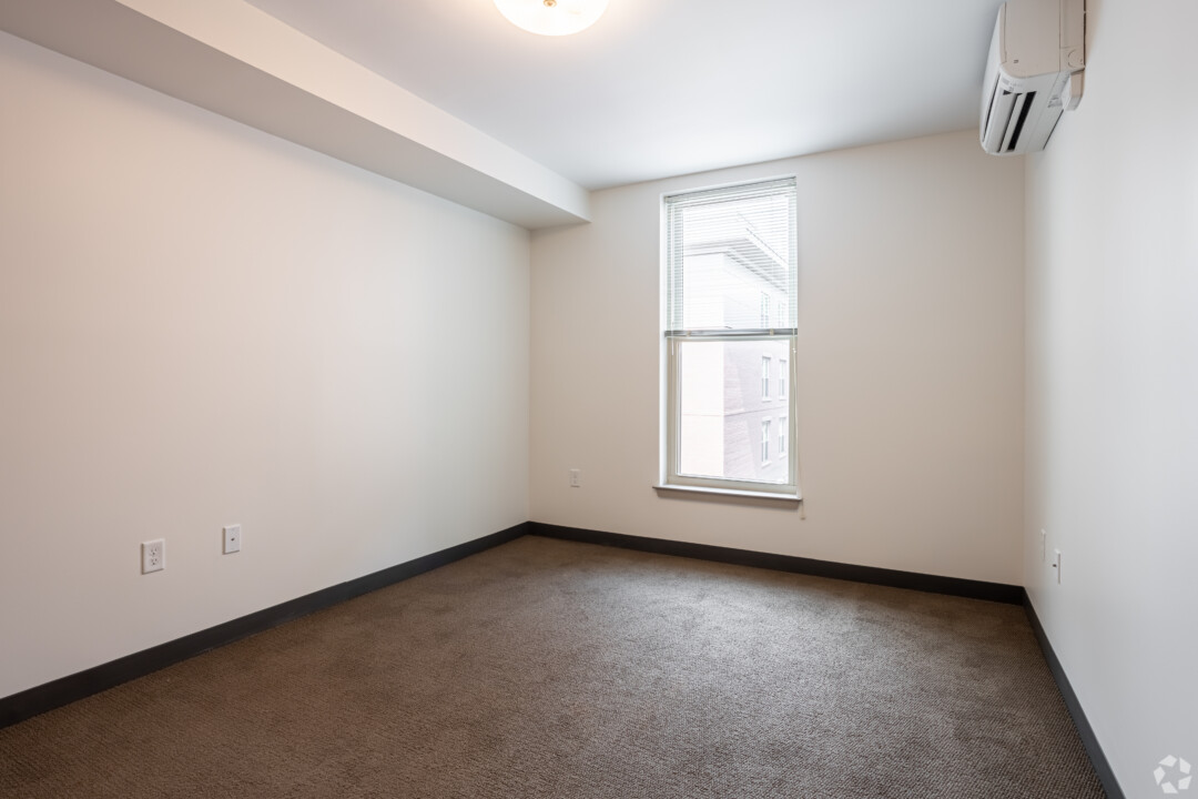 Bedroom with dark carpet flooring, white walls, a window, and a white ceiling.
