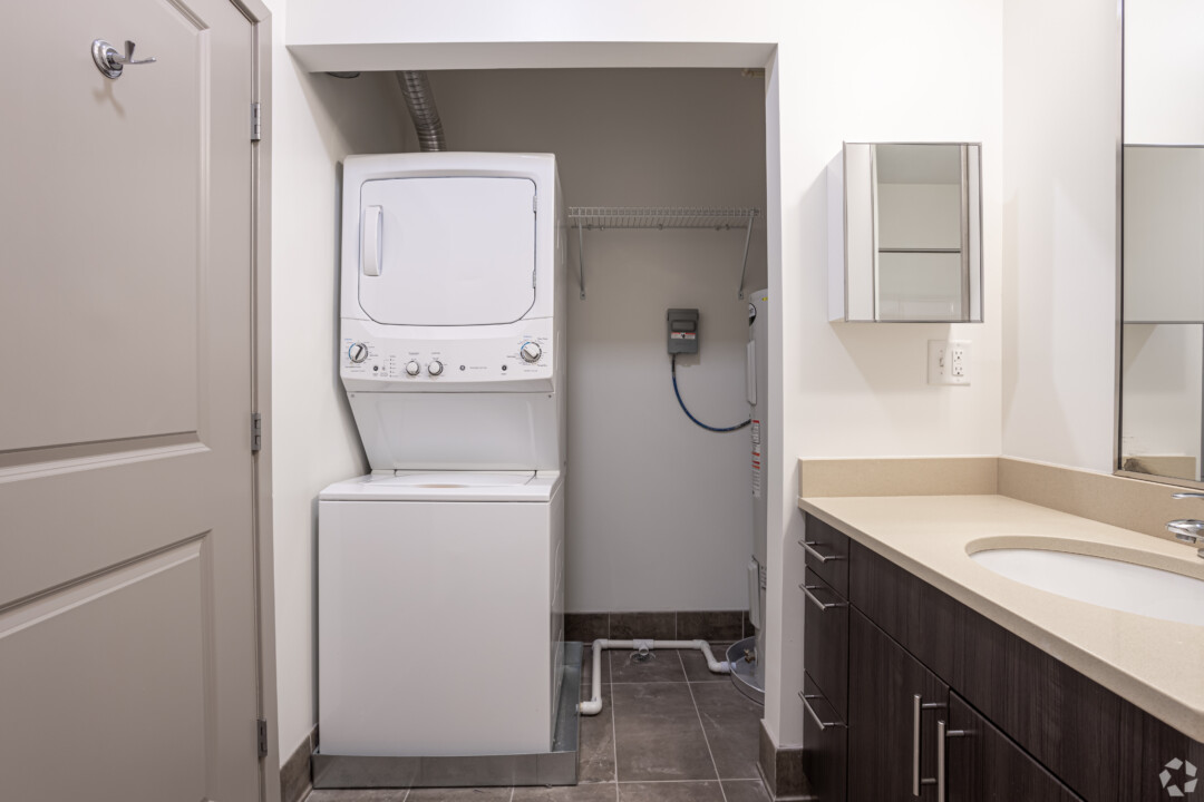 Bathroom with tile flooring, white walls, a white ceiling, a vanity, and an in-unit stacked washer and dryer.