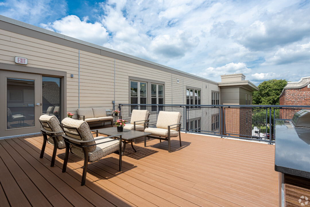 Rooftop deck with wood decking, outdoor furniture, and views of neighboring buildings.