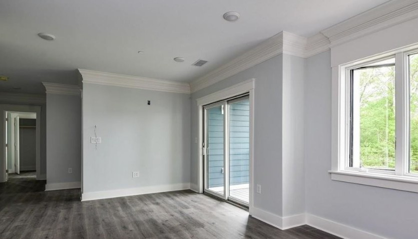 iving room with gray wood-look flooring, light gray walls, white trim, a white ceiling, large windows, and a sliding glass door.