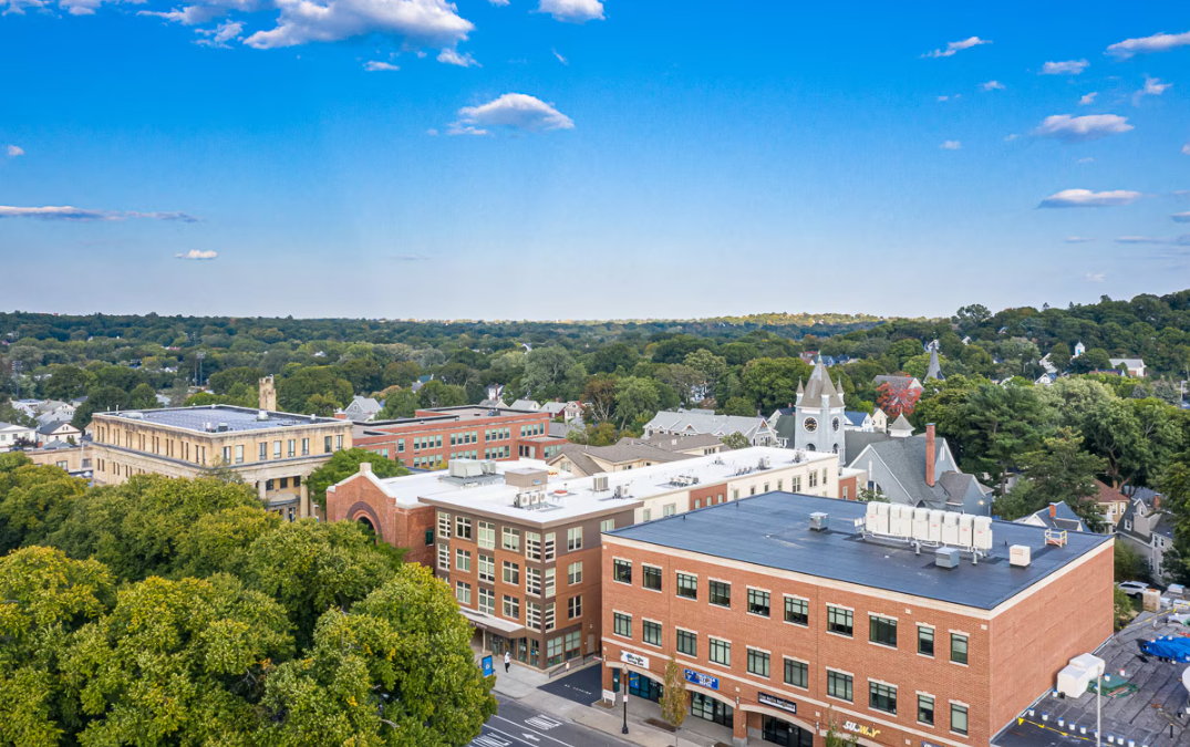Aerial view of the apartment building and surrounding neighborhood under a blue sky.