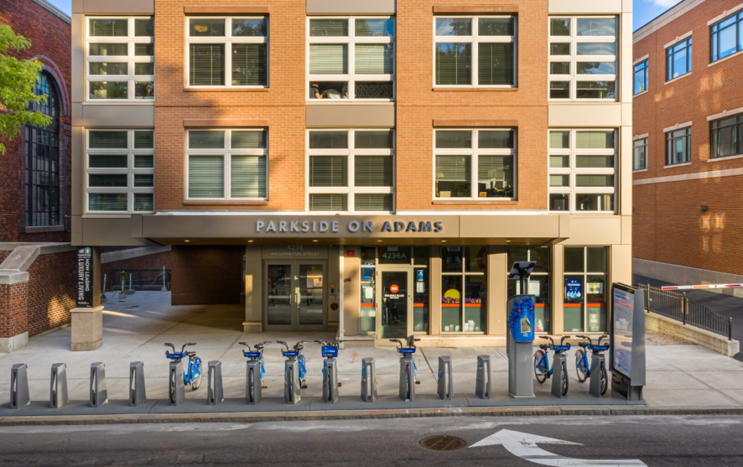 Apartment building entrance with a bike share station in front.