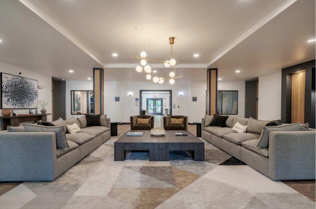 Spacious community lounge with sofas, armchairs, coffee tables, and modern lighting.
