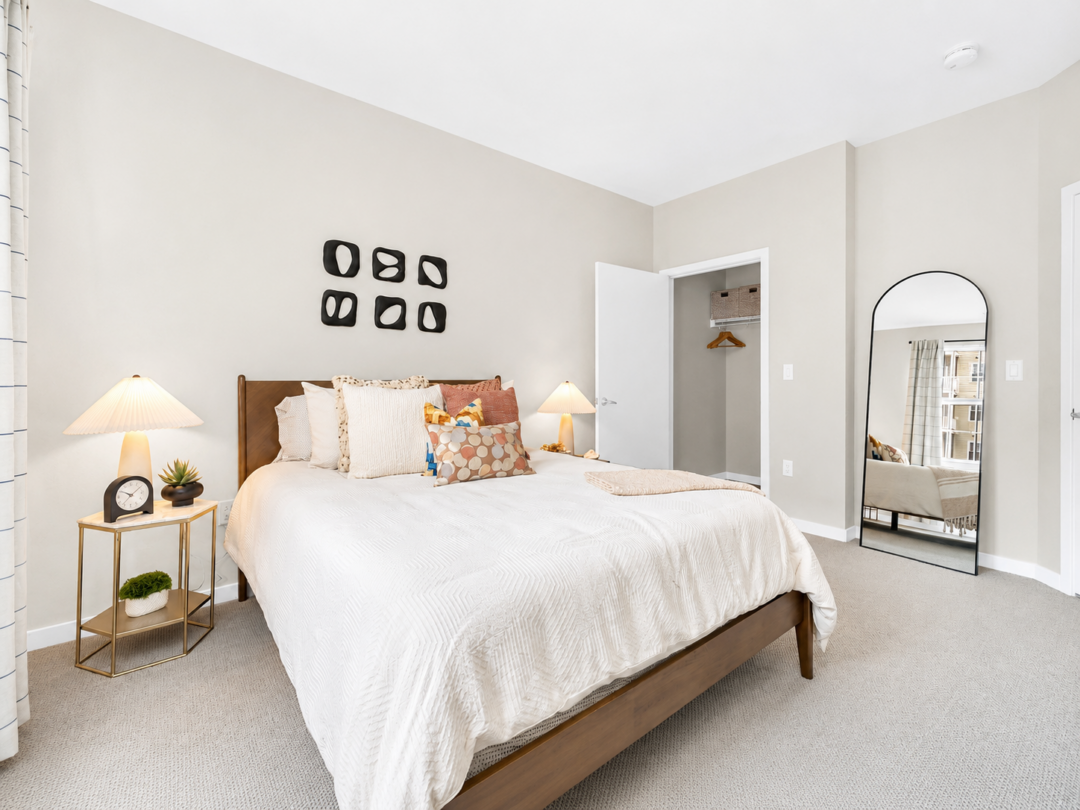 Bedroom with a white bed, bedside lamps, framed wall art, and an open closet.