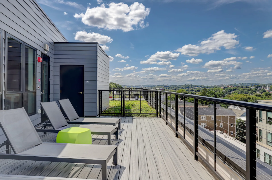 Rooftop deck with lounge chairs and views of the surrounding neighborhood.