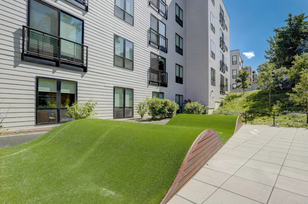 Outdoor courtyard with curved artificial turf mounds beside the apartment building.