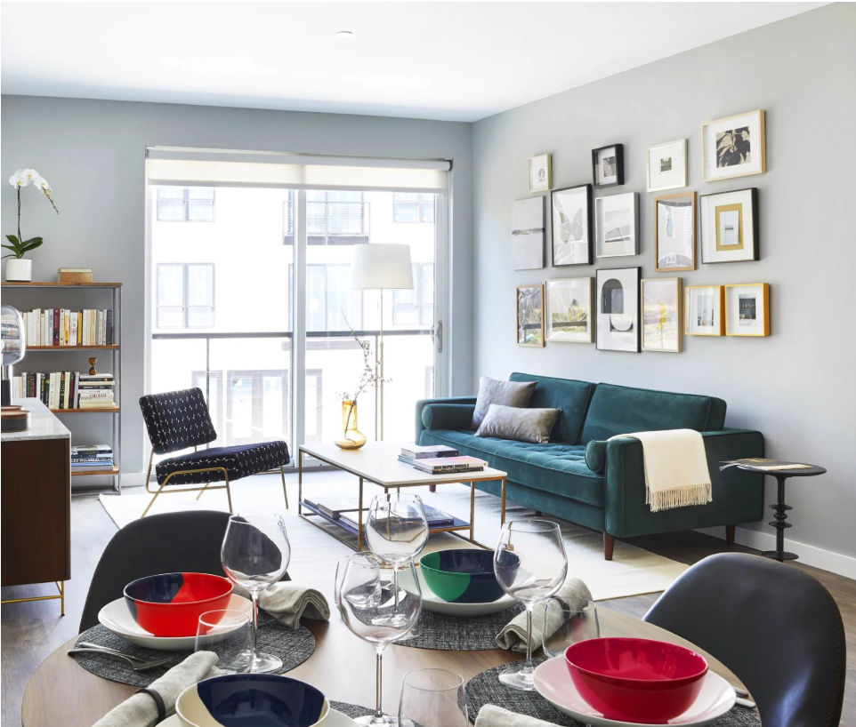 Dining table set with colorful bowls beside a living area with a teal sofa.