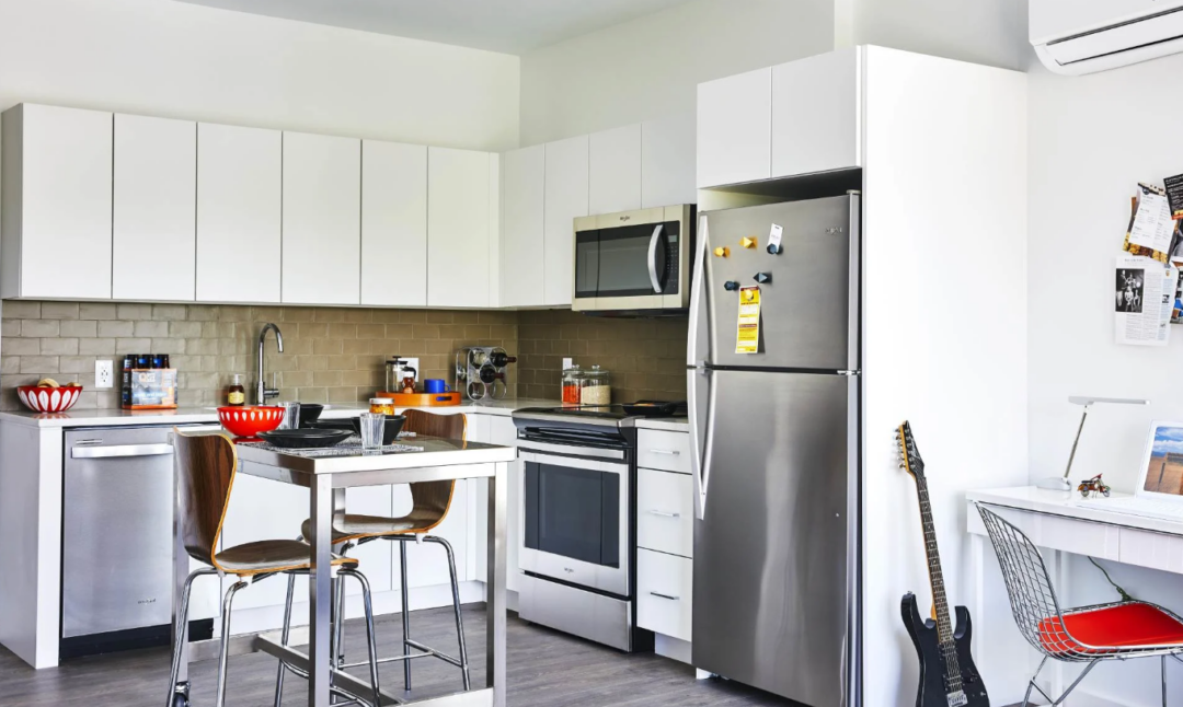 Kitchen with white cabinets, stainless steel appliances, and a tall table with stools.