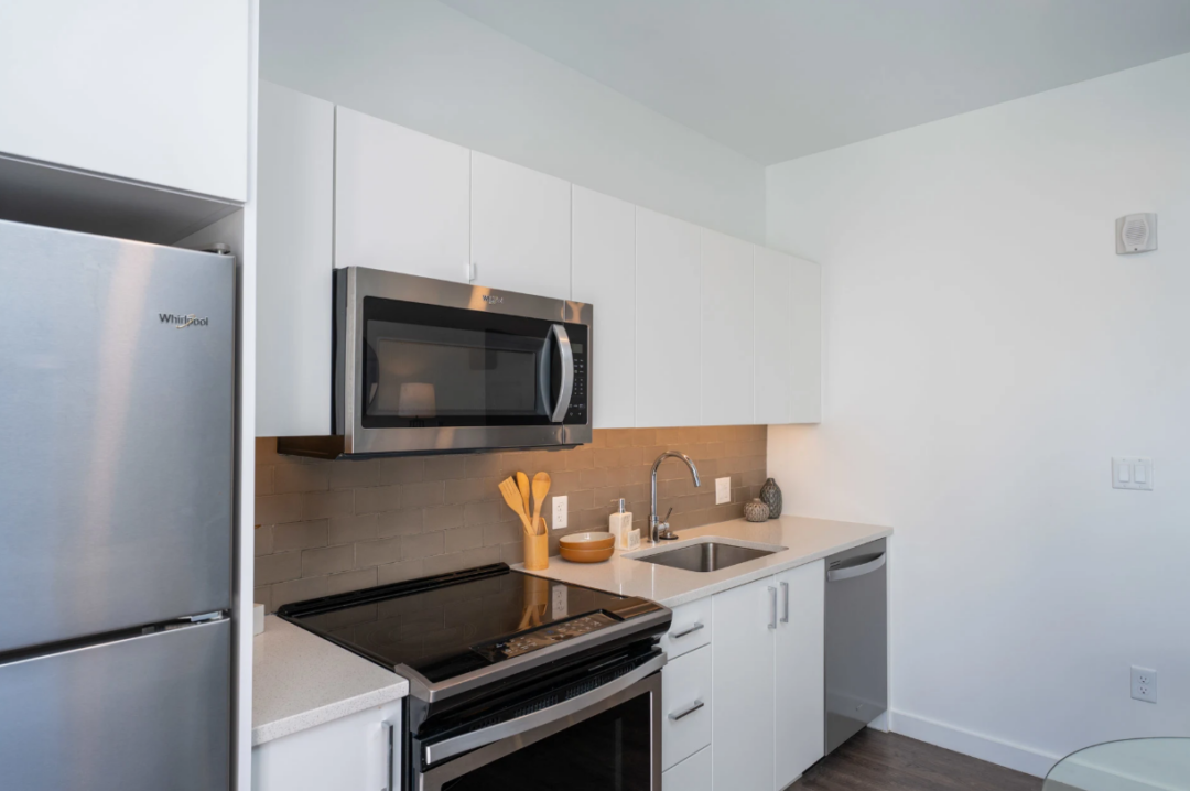 Kitchen with white cabinets, stainless steel appliances, a sink, and a tile backsplash.