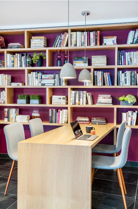 Shared workspace with a wooden table, chairs, pendant lights, and bookshelves.