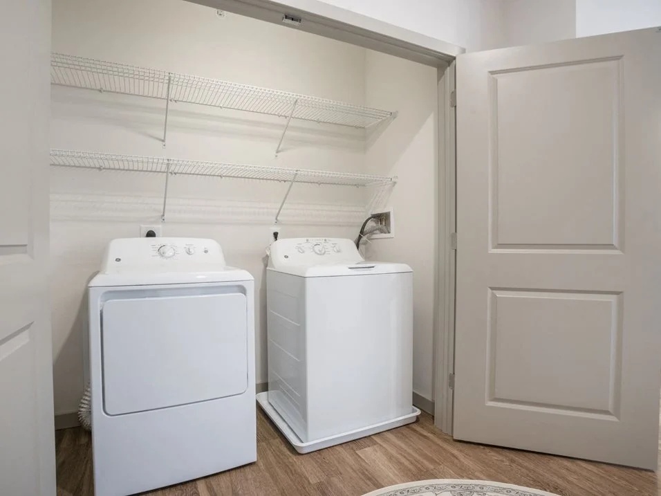 Laundry closet with a washer, dryer, and wire shelving.