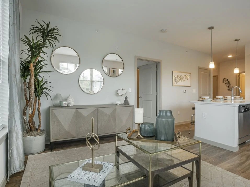 Living room with a sofa, glass coffee table, and wall mirrors.