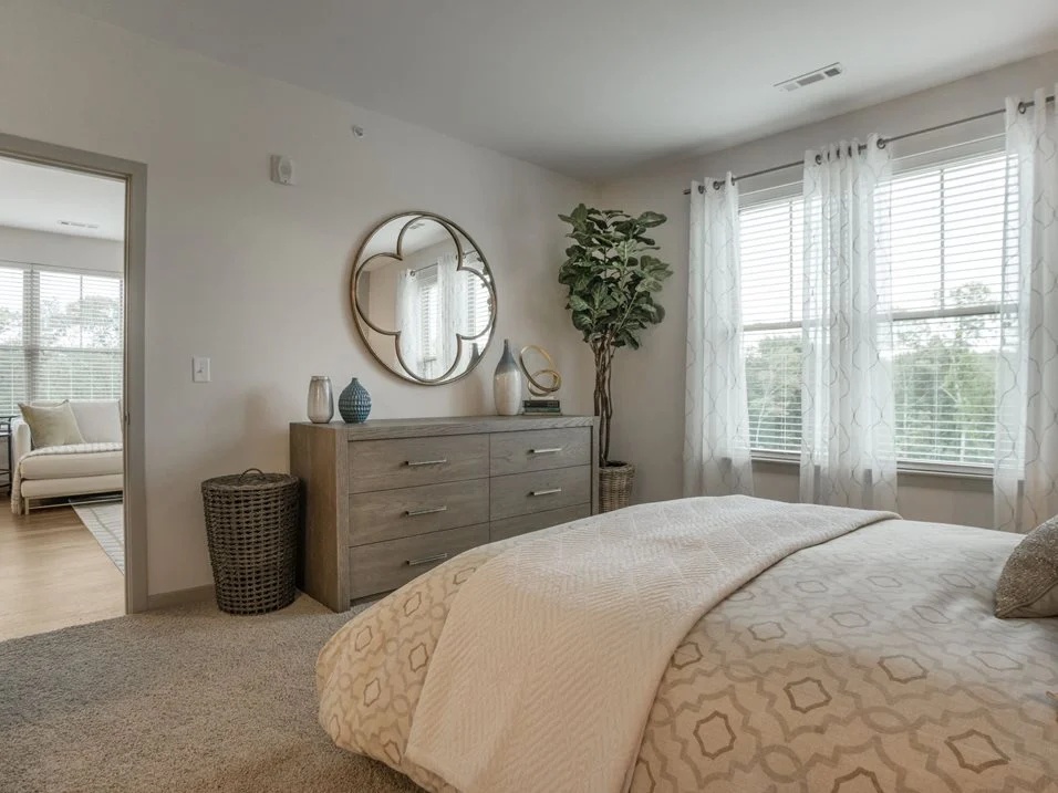 Bedroom with a bed, dresser, and round mirror.