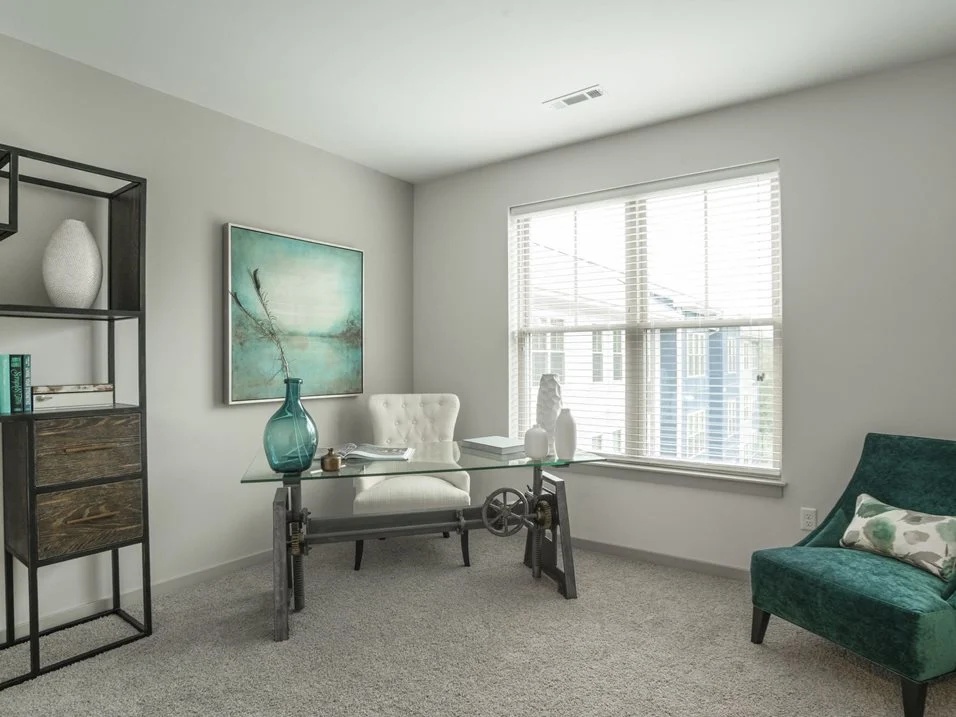 Room with a glass desk and chair beside a window.