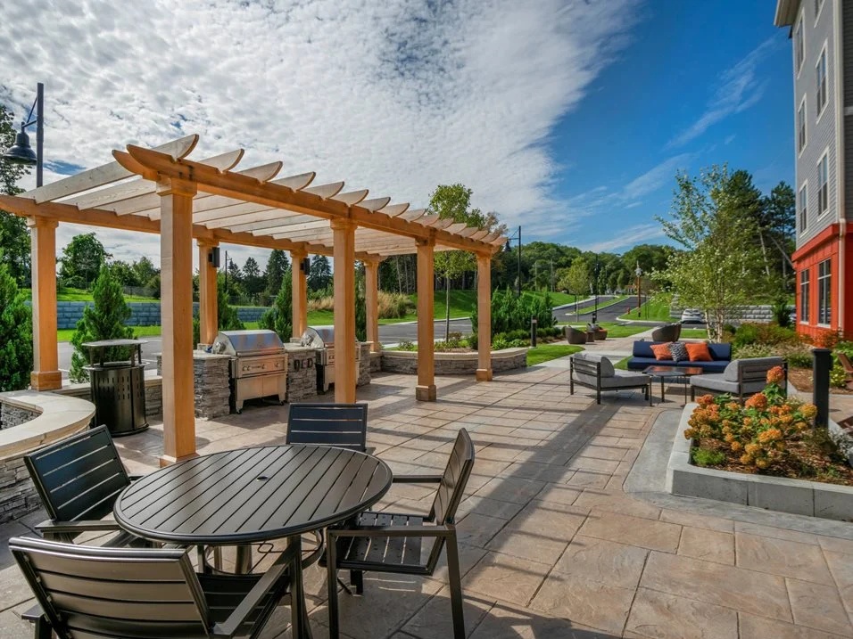 Outdoor patio with tables, chairs, and a wooden pergola.